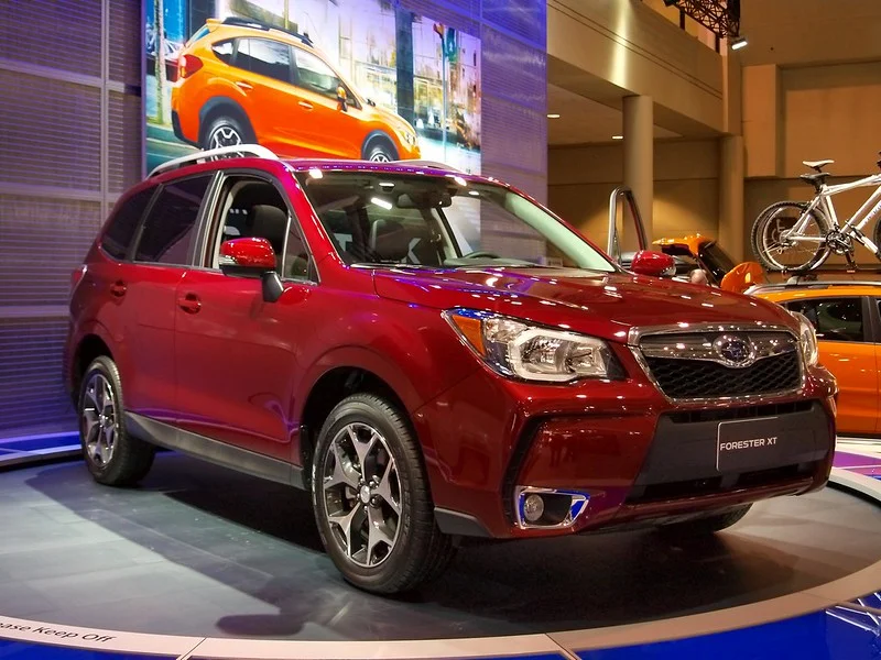 Red 2014 Subaru Forester in a showroom